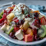 Rainbow fruit table with coconut whipped cream, featuring vibrant strawberries, pineapple, kiwi, and blueberries arranged in rows.