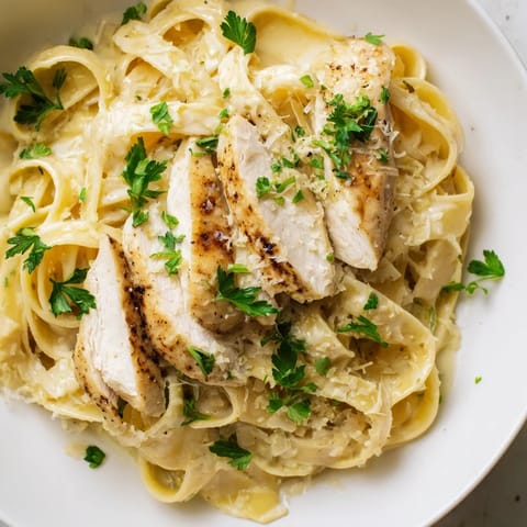 Golden, al dente fettuccine Alfredo, glistening with a rich cream and Parmesan cheese sauce.