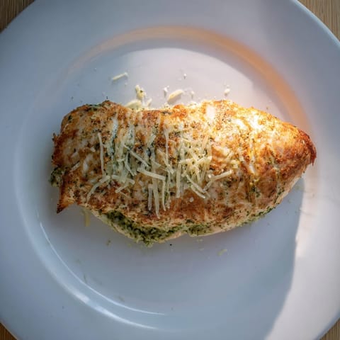 Juicy Italian-style stuffed chicken breast filled with basil pesto and mozzarella, paired with a crisp green salad.