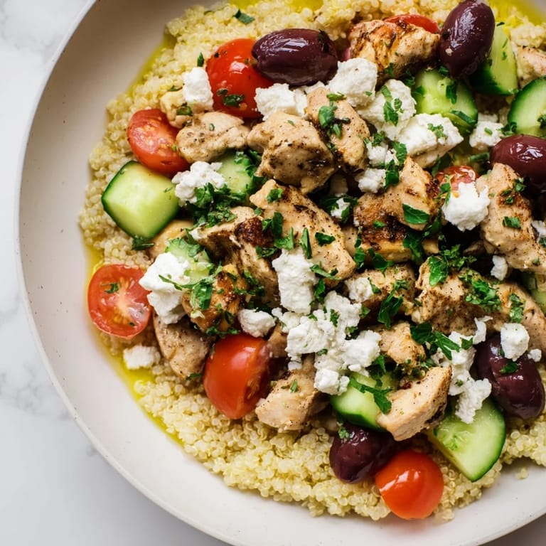 Savory Mediterranean Chicken Bowl featuring tender chicken, fluffy quinoa, chickpeas, cucumber, tomatoes, olives, and feta, all tossed in a bright lemon dressing.