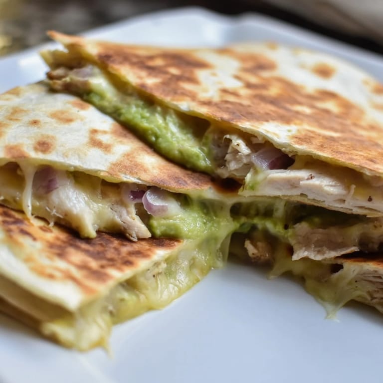 A plate of Chicken Avocado Quesadilla served with fresh salsa and lime wedges for dipping.
